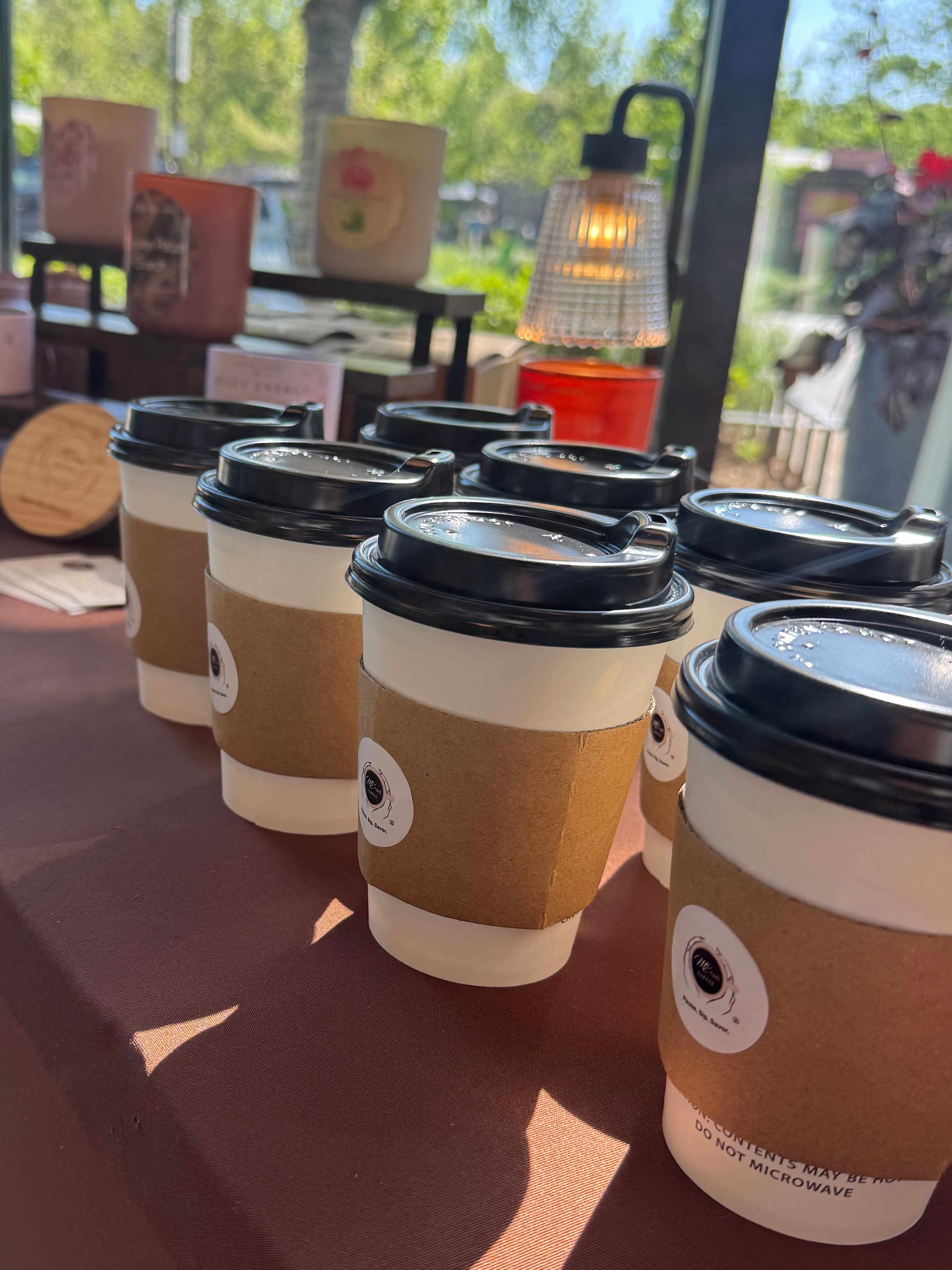 Row of coffee cups with lids on a reflective surface, indoor setting