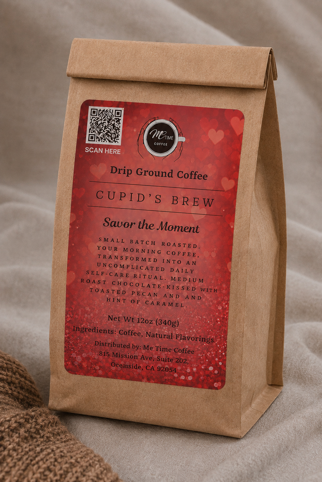 A kraft paper coffee bag standing upright on a neutral fabric surface. The bag has a large red label reading 'CUPID'S BREW' and 'Drip Ground Coffee,' with a small circular logo that appears to say 'Me Time Coffee.